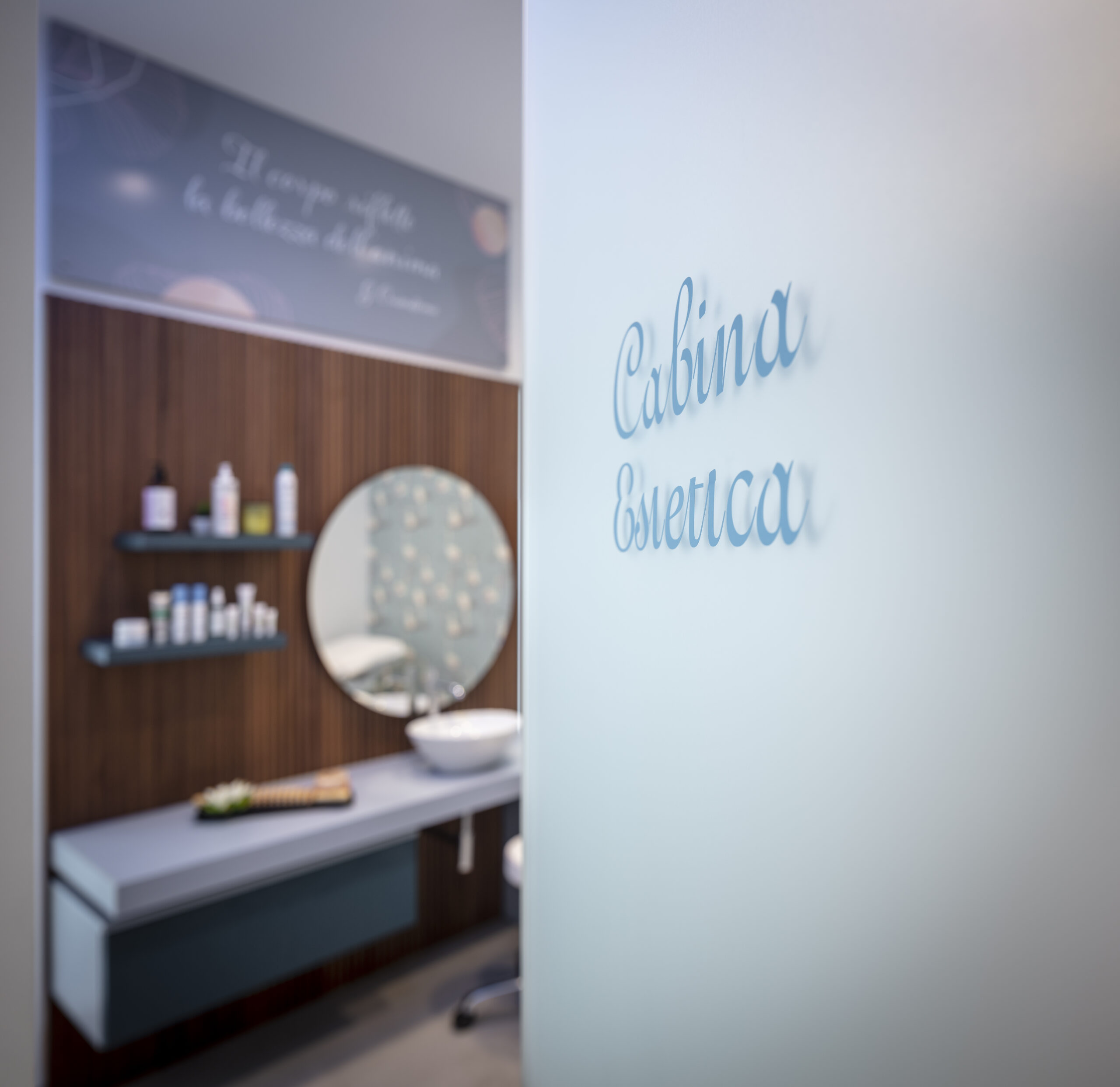 La porta di ingresso di una cabina estetica in farmacia. Sullo sfondo si intravede l’arredamento su misura, realizzato da Th.Kohl.